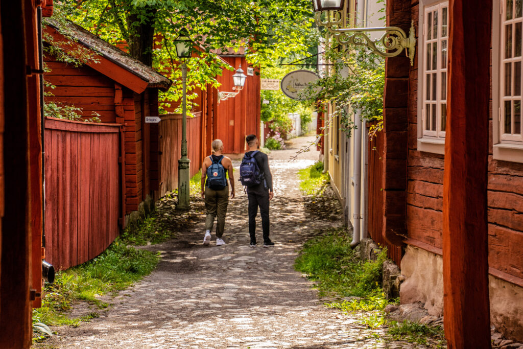 två turister går på en kullerstensgata mellan röda trähus